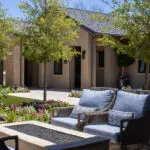 Custom front yard design with trees, fire table and organized planting.
