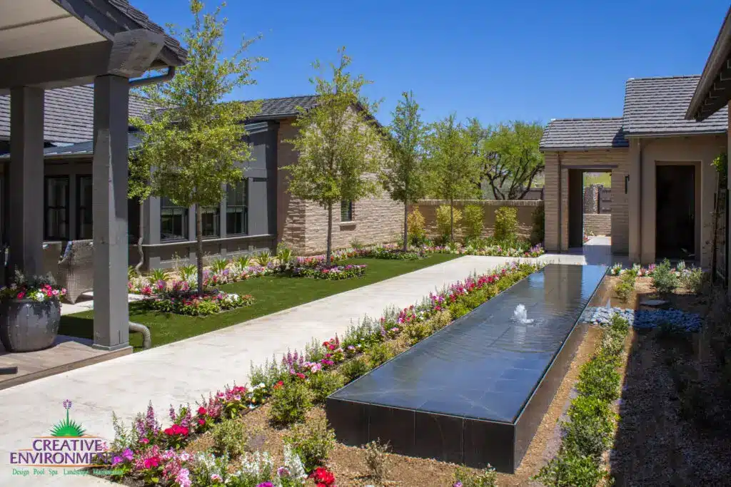 Custom backyard design with organized planting, black water feature and planters.
