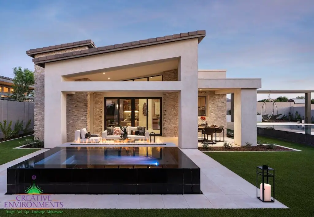 Custom backyard design with black tiled hot tub, artificial turf and hanging swing.