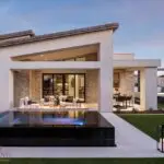 Custom backyard design with black tiled hot tub, artificial turf and hanging swing.