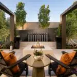 Custom backyard design metal scupper water feature, trees and square fire pit.