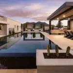 Custom metal shade structure with outdoor BBQ, multiple seating areas and black zero edge pool.