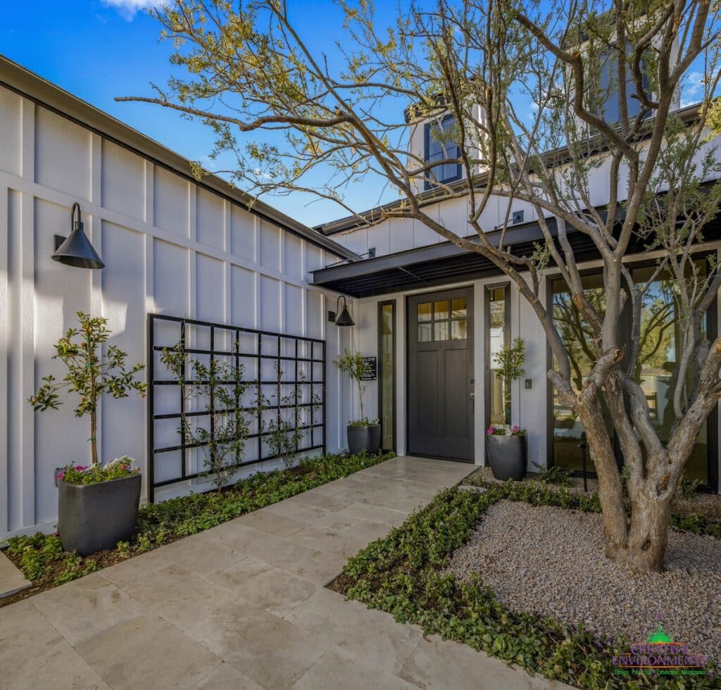 Custom front yard design with organized planting, multiple potted plants and tree.