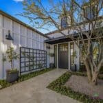 Custom front yard design with organized planting, multiple potted plants and tree.
