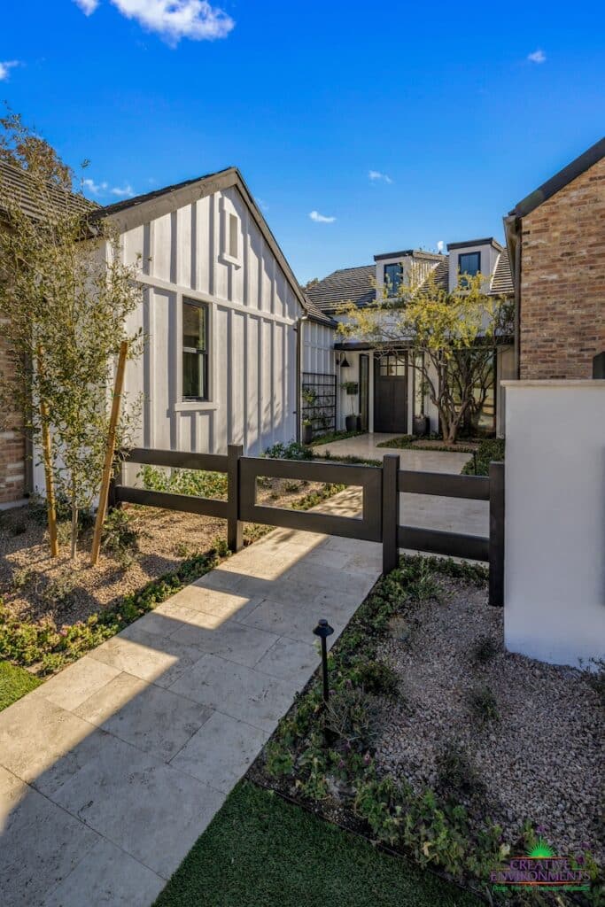 Custom front yard design with organized planting, metal trellis and travertine walkway.