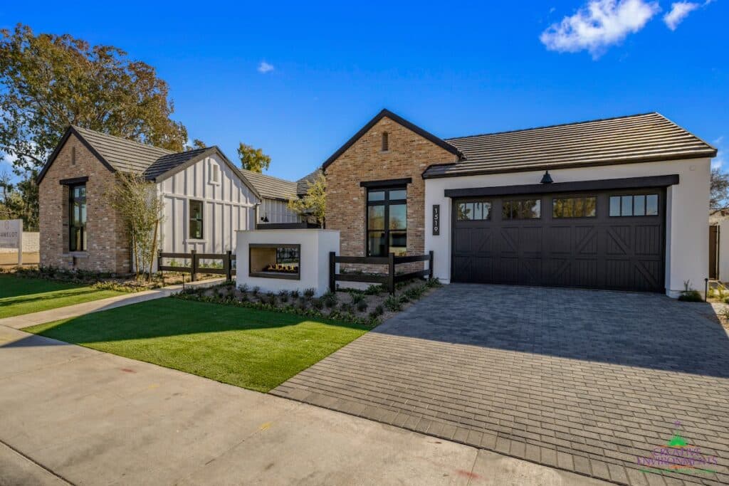 Custom front yard design with paver driveway, built-in fireplace and organized planting.