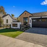 Custom front yard design with paver driveway, built-in fireplace and organized planting.