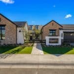 Custom front yard design with multiple grassy areas, built-in fireplace and metal gate.