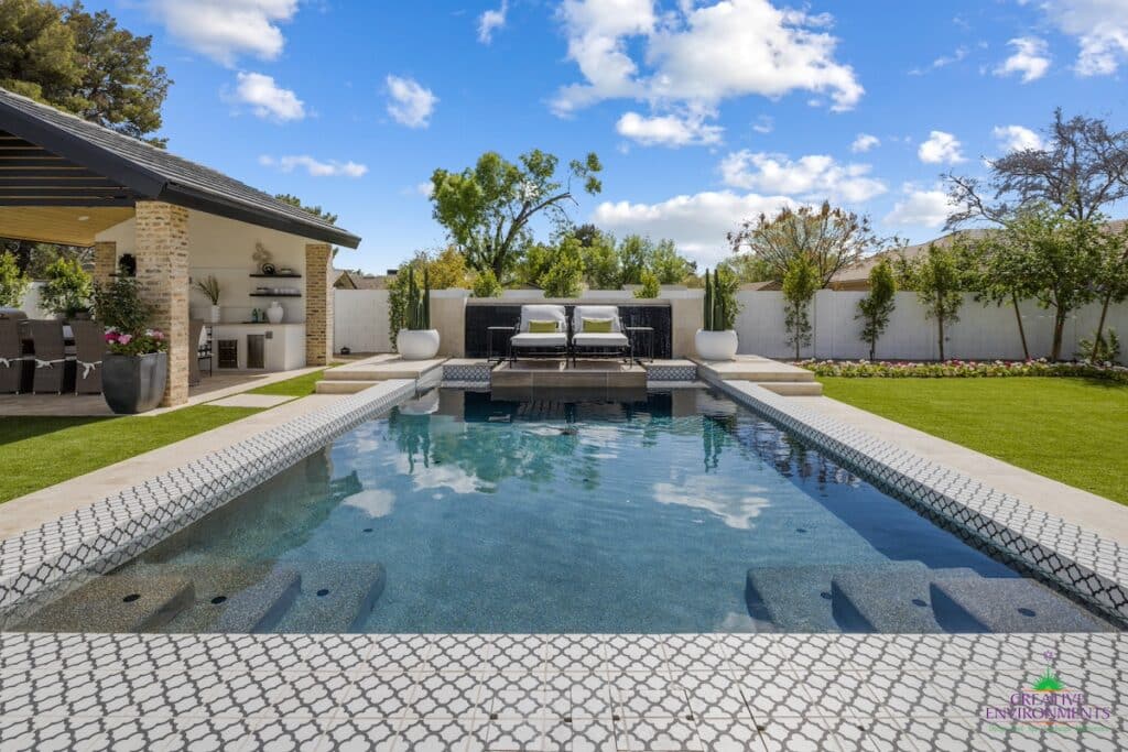 Custom backyard design with deco-tile pool, large potted plants and outdoor shade stucture.