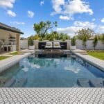 Custom backyard design with deco-tile pool, large potted plants and outdoor shade stucture.