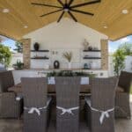 Custom backyard design with outdoor shade structure, outdoor shelving and large potted plants.