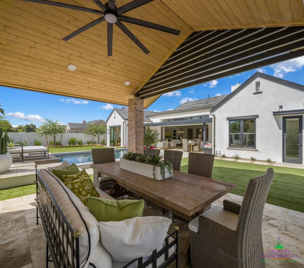 Custom backyard design with shade structure, outdoor fan and multiple seating areas.