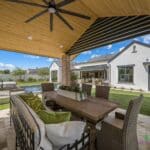 Custom backyard design with shade structure, outdoor fan and multiple seating areas.