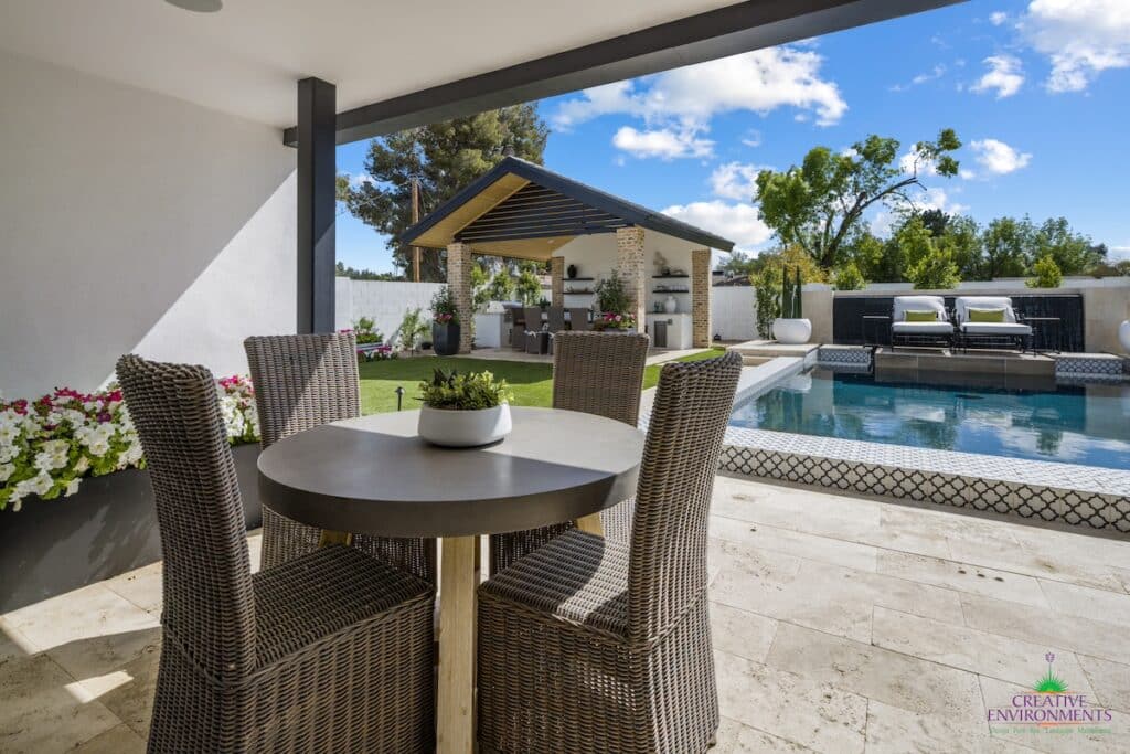 Custom backyard design with large potted plants, multiple seating areas and outdoor shade structure.