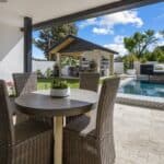 Custom backyard design with large potted plants, multiple seating areas and outdoor shade structure.