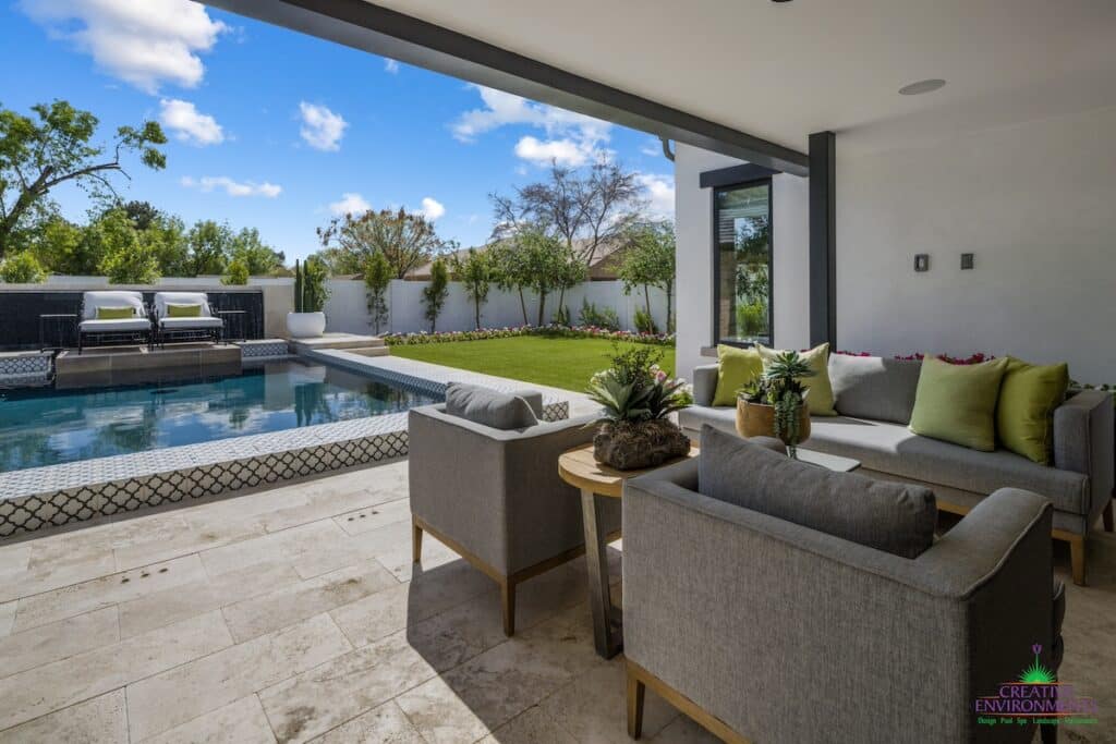 Custom backyard design with deco-tile pool, multiple seating areas and large potted plants.