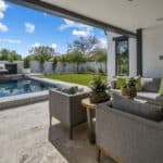 Custom backyard design with deco-tile pool, multiple seating areas and large potted plants.