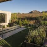 Custom backyard design with garden, custom metal cutouts and multiple seating areas under shade structure.