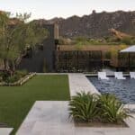Custom backyard design with artificial grass, custom metal dividers and large baja step in black pool.