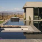 Custom backyard design with sunken fire table with fireballs, zero-edge pool and artificial grass.