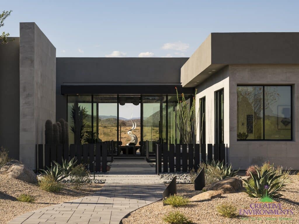 Custom front yard design with metal statement piece, succulents and metal fencing.