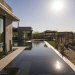 Custom backyard design with zero-edge pool, artificial turf and desert plants.