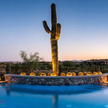 0774Pool(LOGO) Custom backyard design with blue pool, stone retention wall and metal fencing.