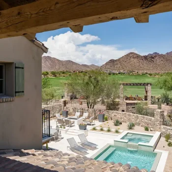 11454-156 Custom backyard design with natural stone accents, multiple seating areas and blue pool and spa.
