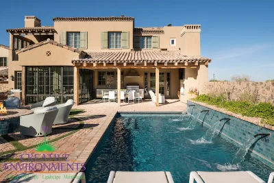Custom backyard design with flowers, water scuppers into pool and patterned turf.