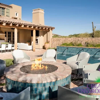 5536Firepit(LOGO) Custom backyard design with stone wall, circular fire pit and multiple seating areas.