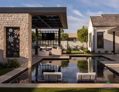 Custom shade structure with floral cutouts, natural stone columns and outdoor TV.