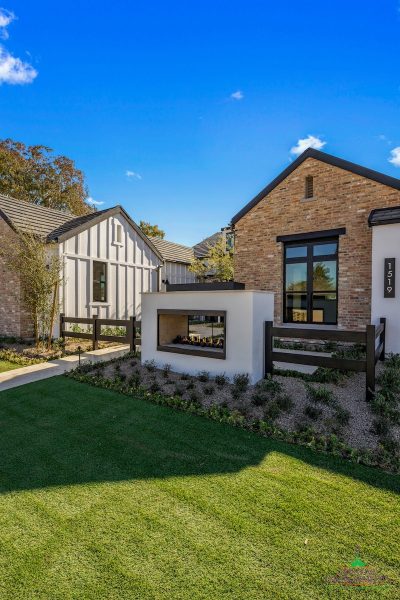 Custom front yard design with organized planting, built-in fireplace and metal gate.