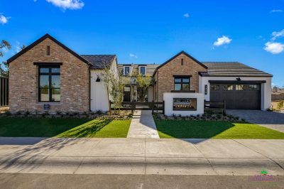Custom front yard design with multiple grassy areas, built-in fireplace and metal gate.