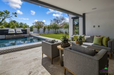 Custom backyard design with deco-tile pool, multiple seating areas and large potted plants.
