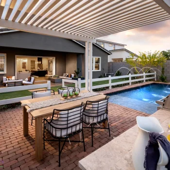 Cadence_Bowie_Patio_2270LOGO Custom backyard design with white metal shade structure, outdoor dining area and artificial turf.