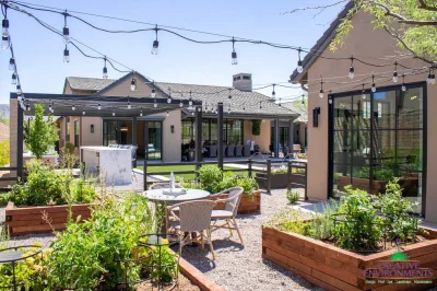 Custom backyard design with string lights, gardening corner and multiple seating areas.