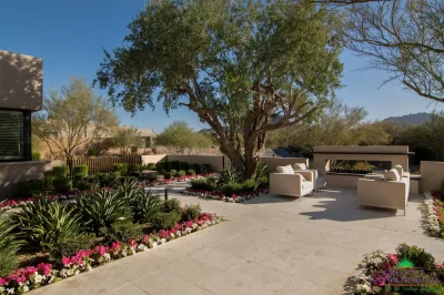 Custom backyard design with fireplace, organized planting and tree.
